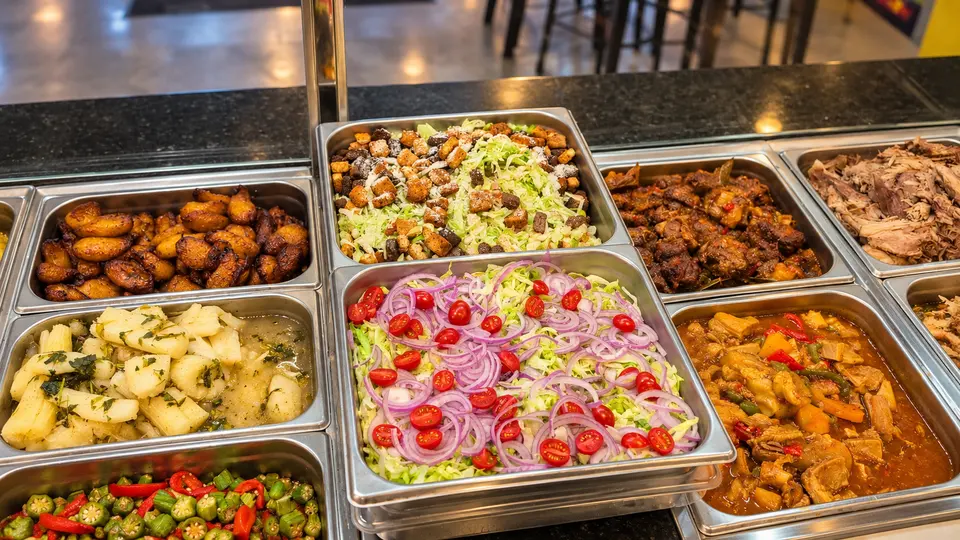 The Daily Buffet hot table with sweet plantains, yuca, salads, stews and okra